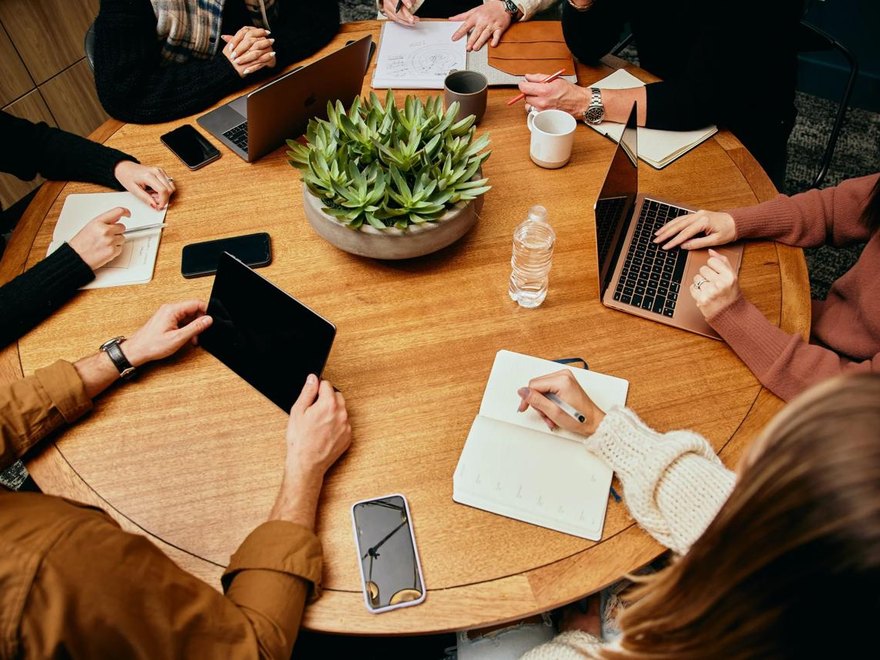 A team collaborating around a table with laptops and notebooks